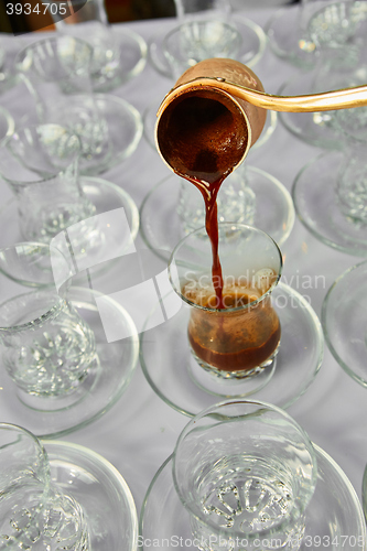 Image of Pouring turkish coffee into traditional embossed cup.