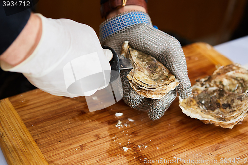 Image of Fresh oyster held open with knife in hand