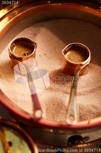 Image of Preparation of Turkish coffee in the cezve in the sand at cafe bar