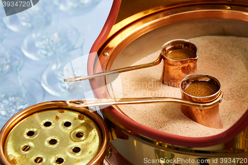 Image of Preparation of Turkish coffee in the cezve in the sand at cafe bar