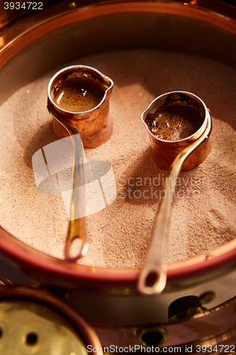 Image of Preparation of Turkish coffee in the cezve in the sand at cafe bar