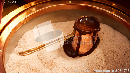 Image of Preparation of Turkish coffee in the cezve in the sand at cafe bar