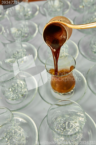 Image of Pouring turkish coffee into traditional embossed cup.