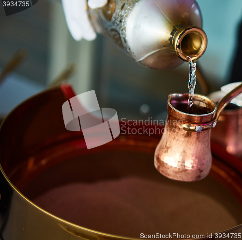 Image of Preparation of Turkish coffee in the cezve in the sand at cafe bar