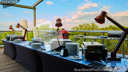 Image of Table with dishware and shiny marmites waiting for guests.