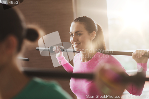 Image of group of people exercising with bars in gym