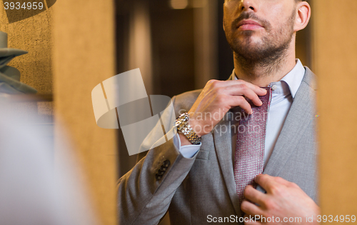 Image of close up of man trying tie on at mirror