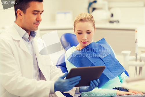 Image of male dentist with tablet pc and woman patient