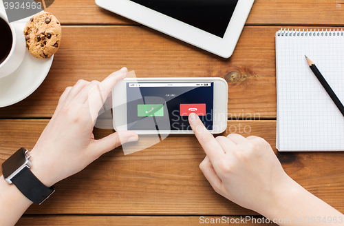 Image of close up of woman with smartphone on wooden table