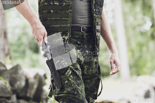 Image of close up of soldier or hunter with knife in forest