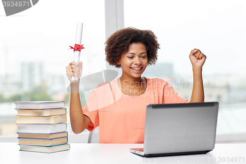 Image of happy african woman with laptop, books and diploma