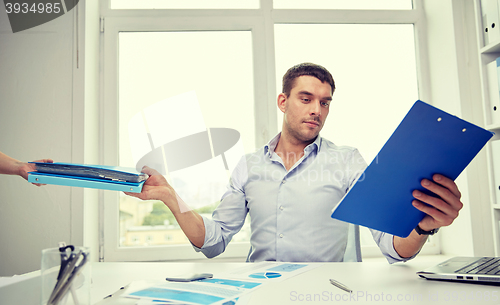 Image of businessman taking papers from secretary in office