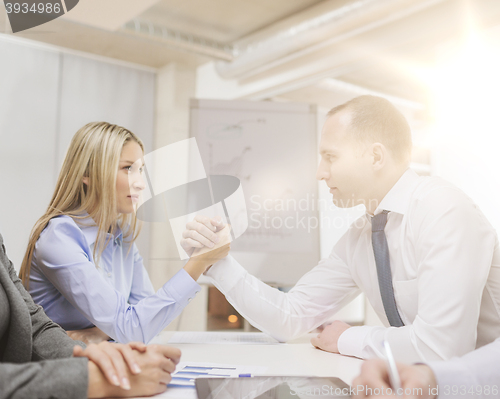 Image of businesswoman and businessman arm wrestling