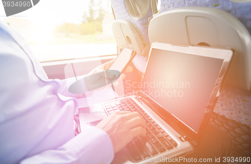 Image of man with smartphone and laptop in travel bus