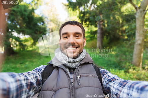 Image of happy man with backpack taking selfie and hiking