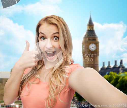 Image of happy woman taking selfie and showing thumbs up