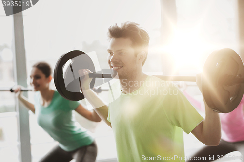 Image of group of people exercising with barbell in gym