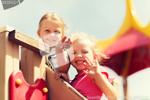 Image of happy girls waving hands on children playground