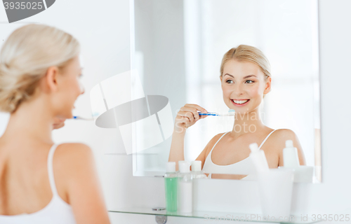 Image of woman with toothbrush cleaning teeth at bathroom