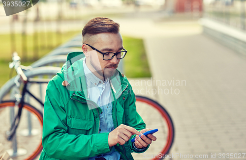 Image of young hipster man with smartphone and byke