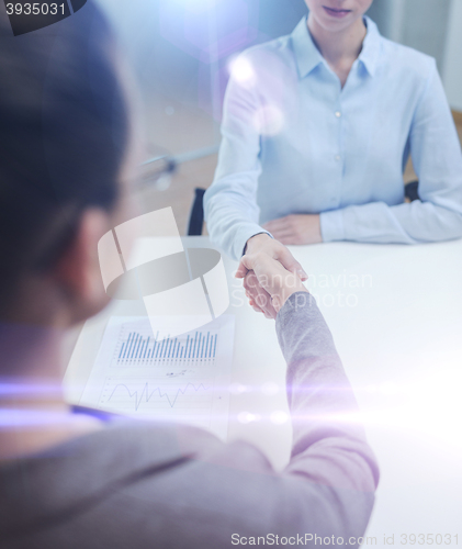 Image of two calm businesswoman shaking hands in office