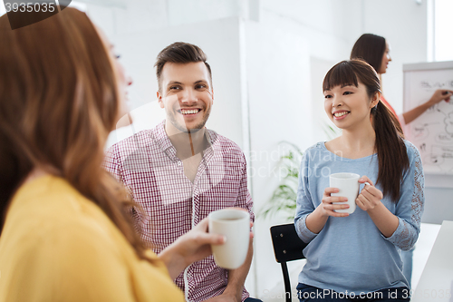 Image of happy creative team drinking coffee at office