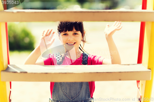Image of happy little girl climbing on children playground