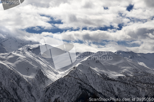 Image of View on snowy mountains and sunlight cloudy sky in evening