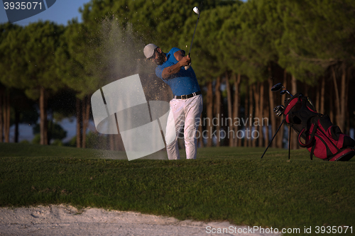 Image of golfer hitting a sand bunker shot on sunset