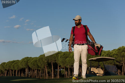 Image of golfer  walking and carrying golf  bag