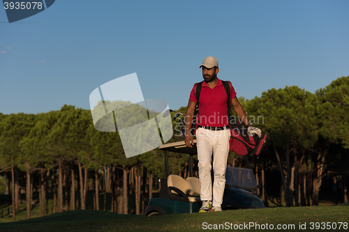 Image of golfer  walking and carrying golf  bag