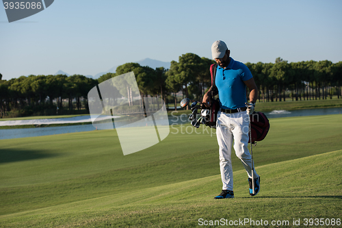 Image of golf player walking and carrying bag