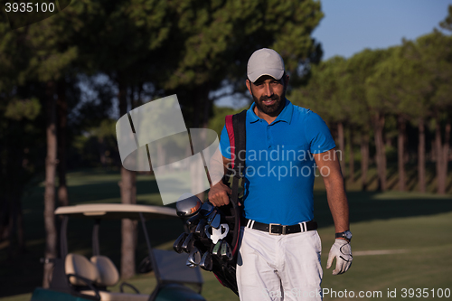 Image of golfer  walking and carrying golf  bag