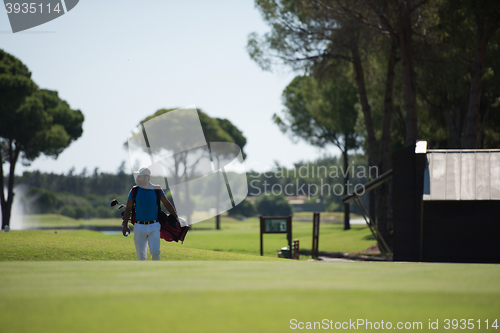 Image of golf player walking and carrying bag