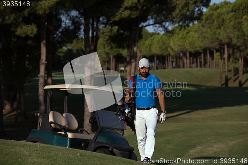 Image of golfer  walking and carrying golf  bag