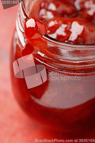 Image of Strawberry jam blob over glass jar screw