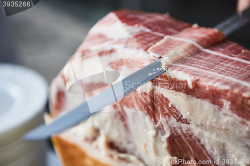 Image of Chef slices serrano ham.