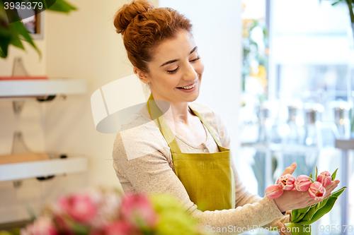 Image of smiling florist woman making bunch at flower shop