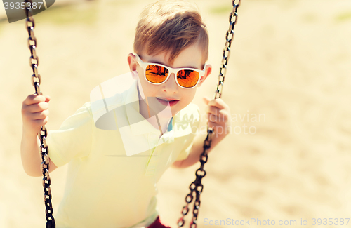 Image of happy little boy swinging on swing at playground