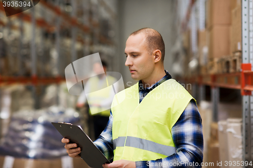 Image of man with clipboard in safety vest at warehouse