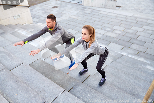 Image of couple doing squats on city street stairs