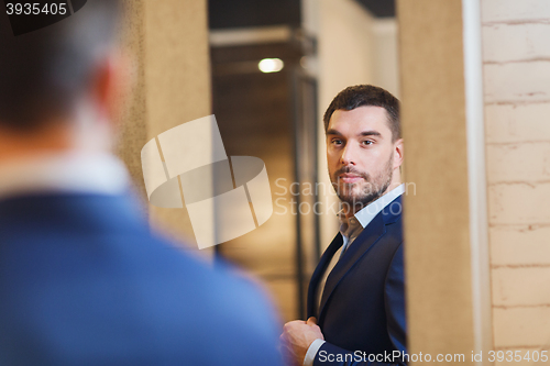 Image of man trying jacket on at mirror in clothing store