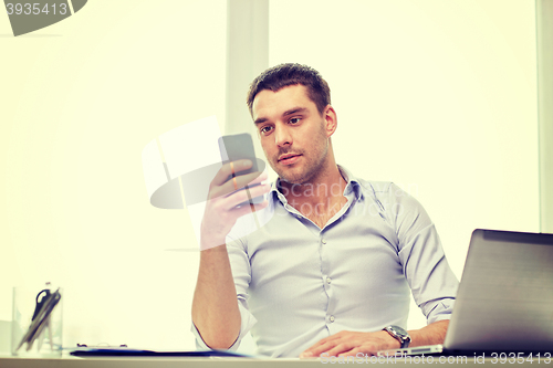 Image of businessman with smartphone and laptop at office