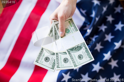 Image of close up of hand with money over american flag