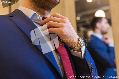 Image of close up of man trying tie on at clothing store