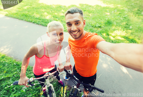Image of couple with bicycle taking selfie outdoors