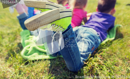 Image of close up of kids lying on picnic blanket outdoors