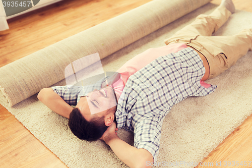 Image of happy man lying carpet or rug at home