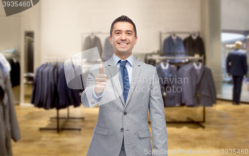 Image of happy businessman in suit over clothing store