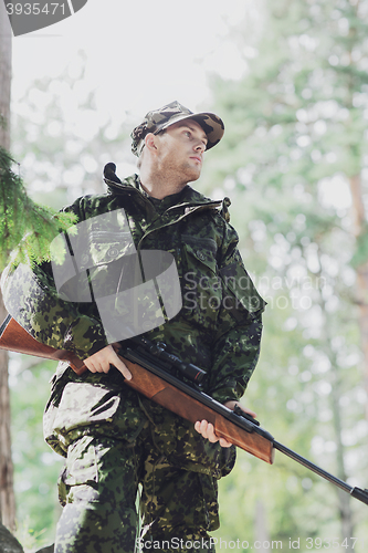 Image of young soldier or hunter with gun in forest